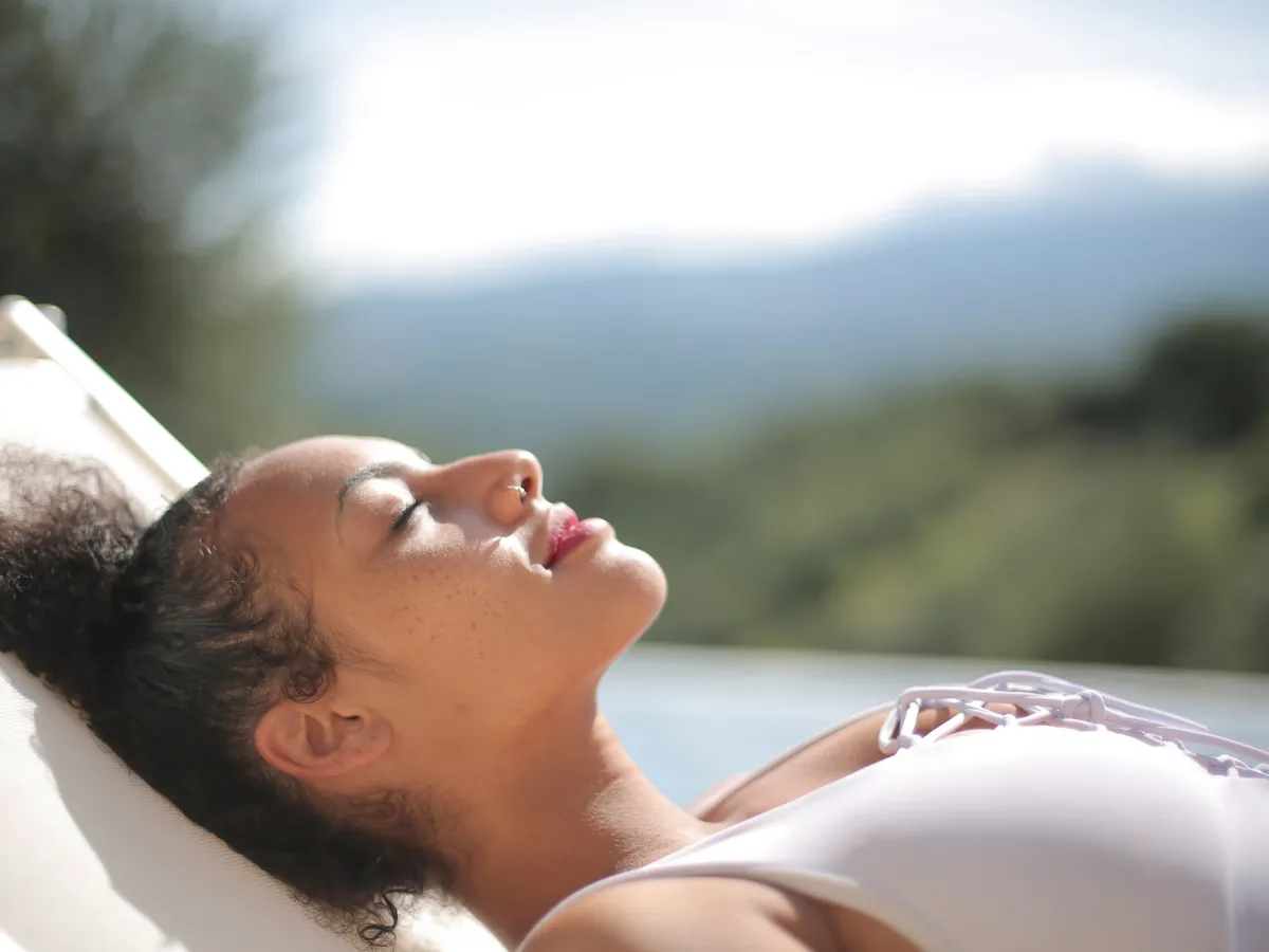 Person receiving LED light therapy facial treatment under a Healite II device at a spa clinic.
